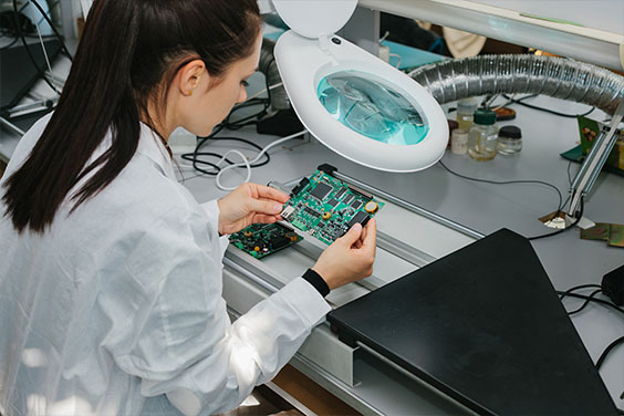 Coreworks employee performing a quality check on a circuit board